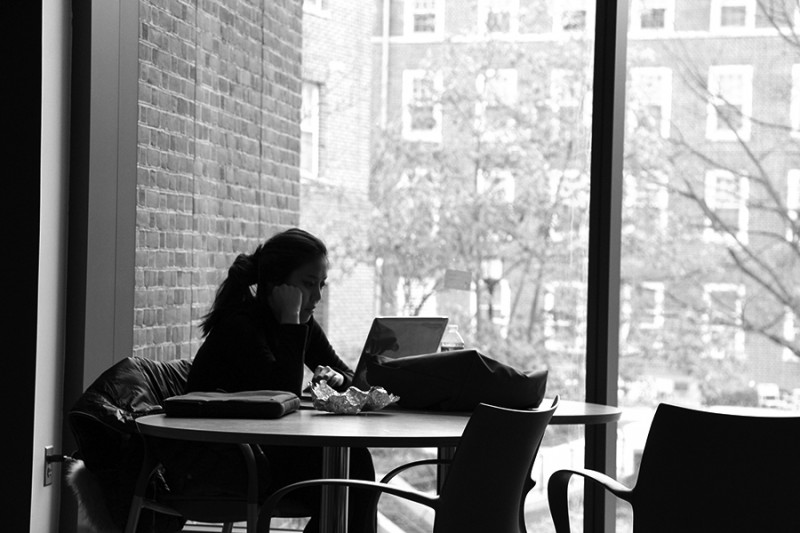 Black and white photo shows a girl against a large window