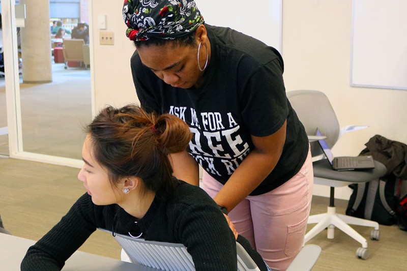 A student gives her peer a backrub. 