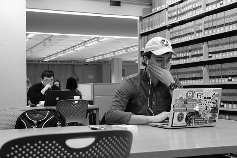 Black and white photo shows a stressed out student covering his mouth with his hand