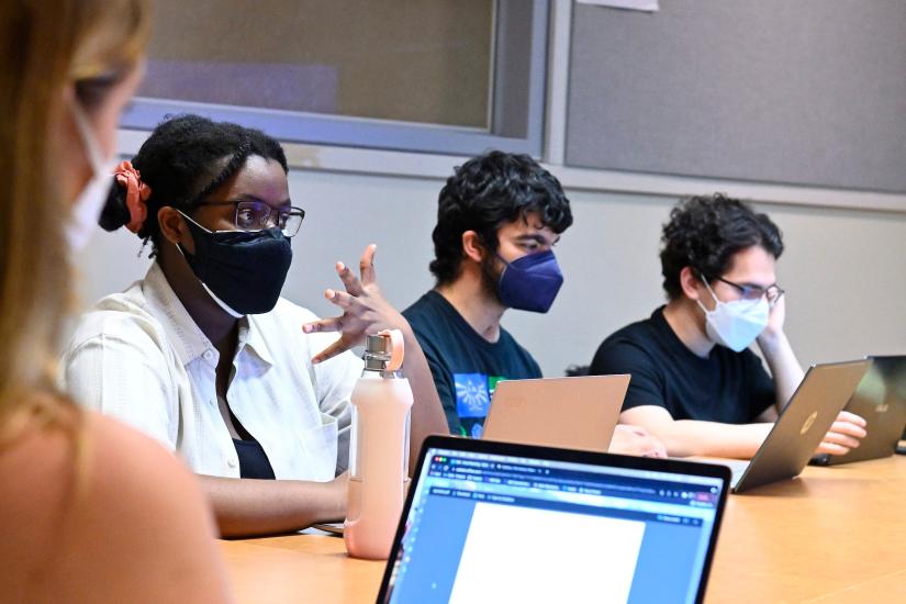 People wearing masks have a roundtable conversation