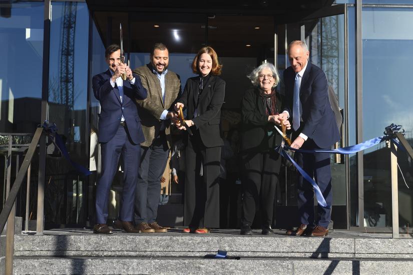 Five people use giant scissors at a ceremonial ribbon cutting event
