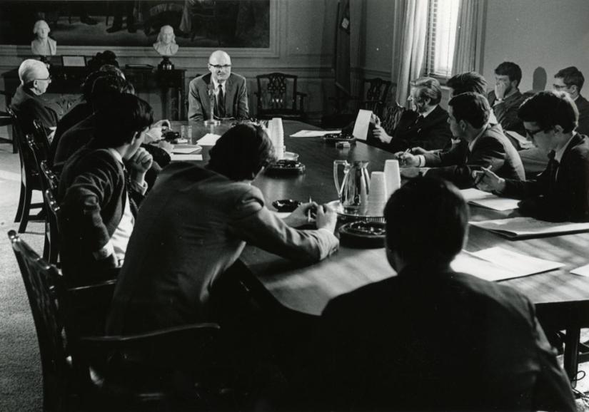 Black and white photo of students seated around a seminar table