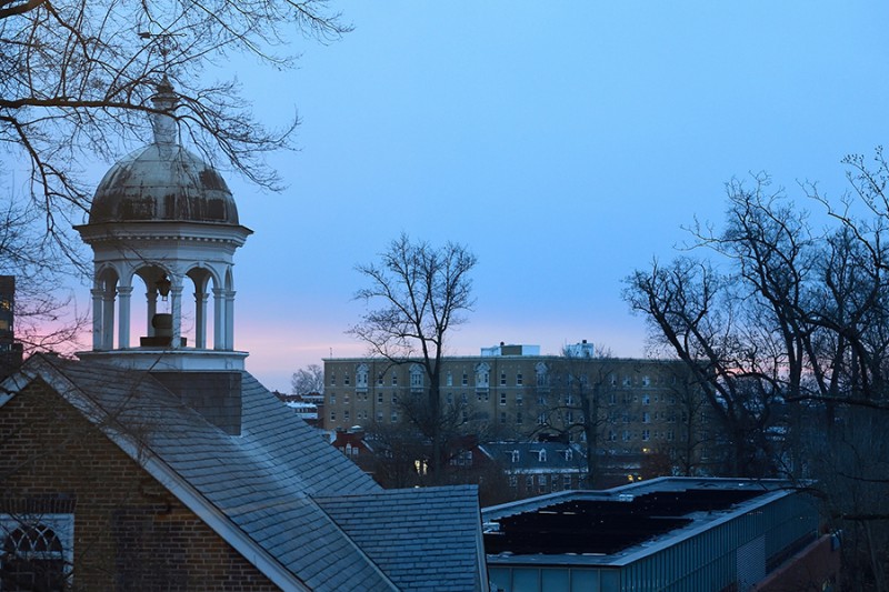 The sun rises in the distance while the Gilman bell tower is in the foreground
