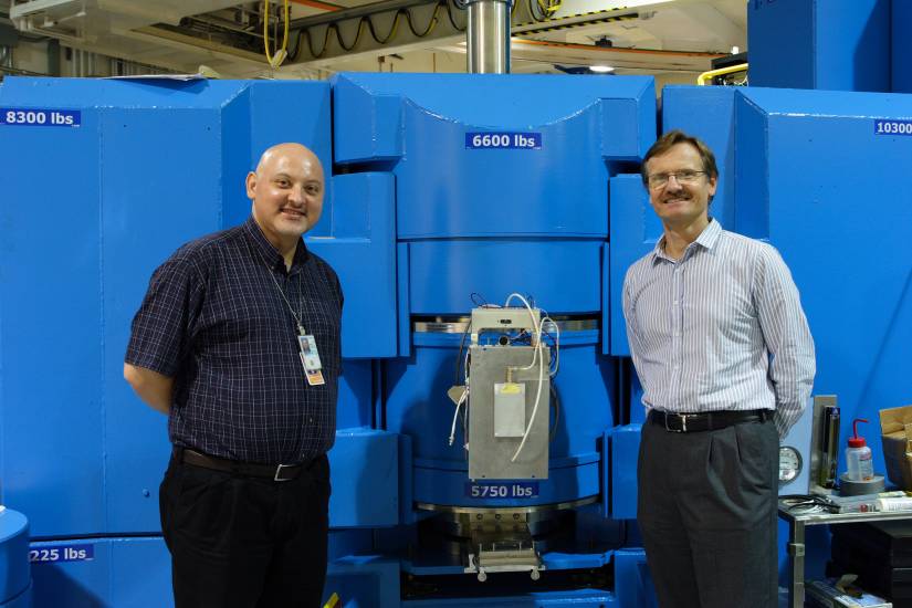 Two men stand beside a large piece of laboratory equipment