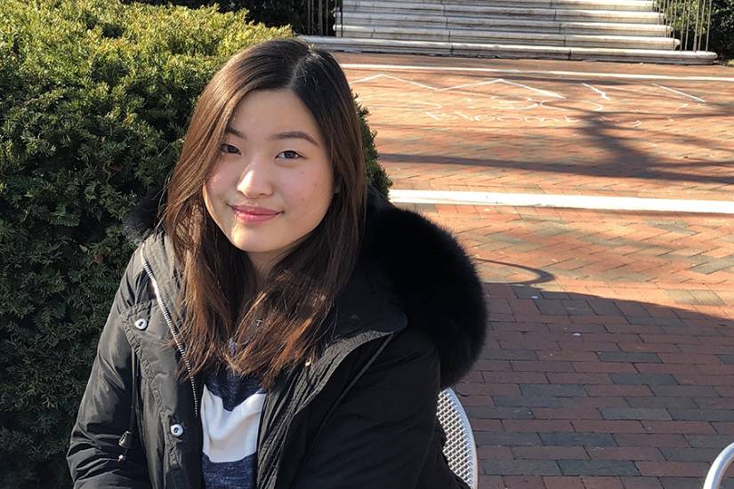 A student smiles on a bench