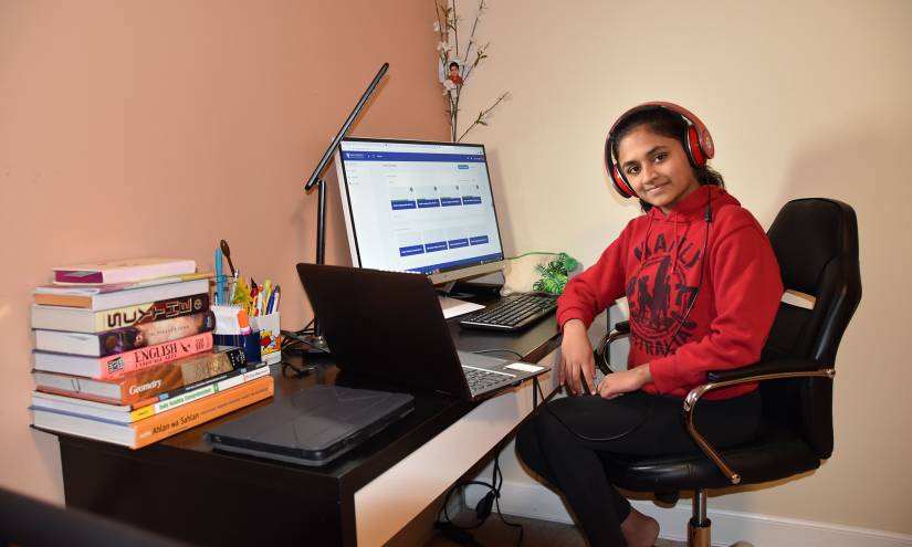 A girl works at a computer desk in her home