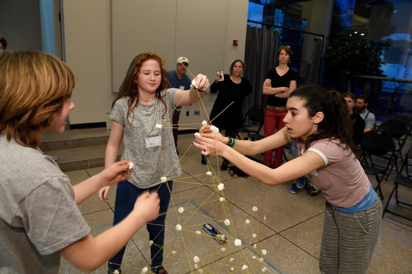 Three students build their tower ever-higher