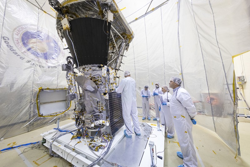 In a room tented in plastic, scientists in lab suits and hair nets inspect the Parker Solar Probe