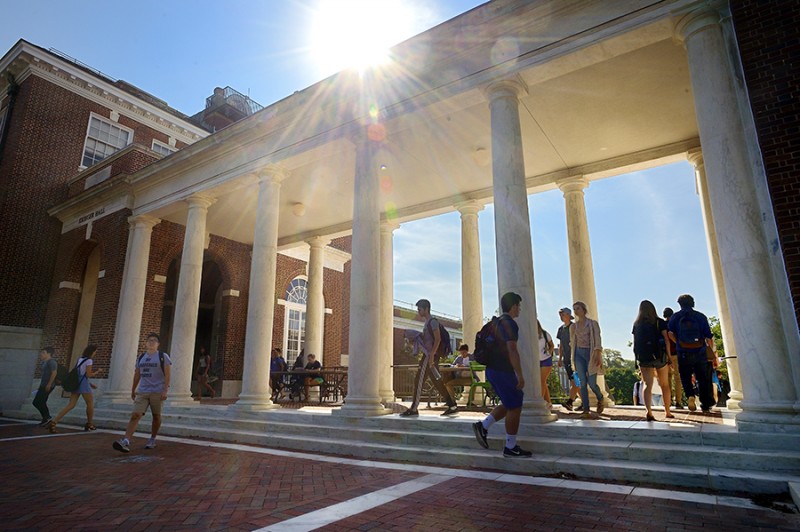 Students walk through the Homewood Campus Breezeway and the sun shines in the background.