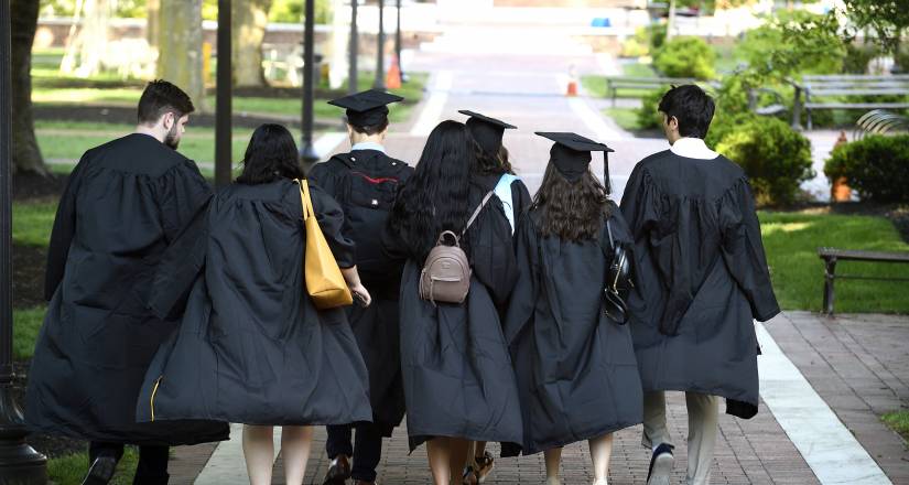 Student walk away from the camera wearing Commencement regalia