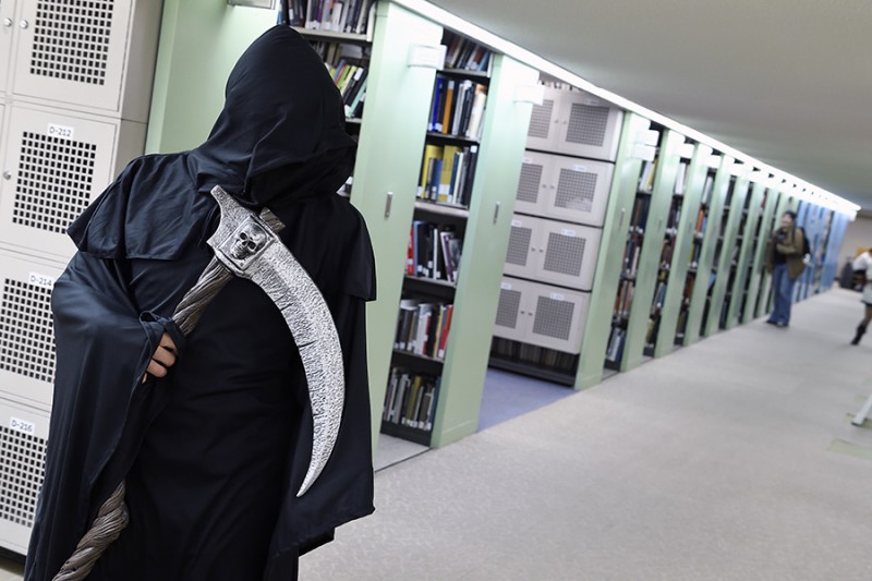 A student is dressed up as the grim reaper against a backdrop of bookcases