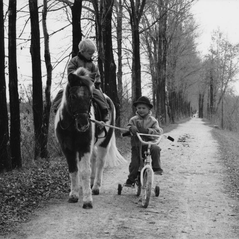 Two boys on the Illinois Prairie Path—one on a bicycle with training wheels, the other on a pony
