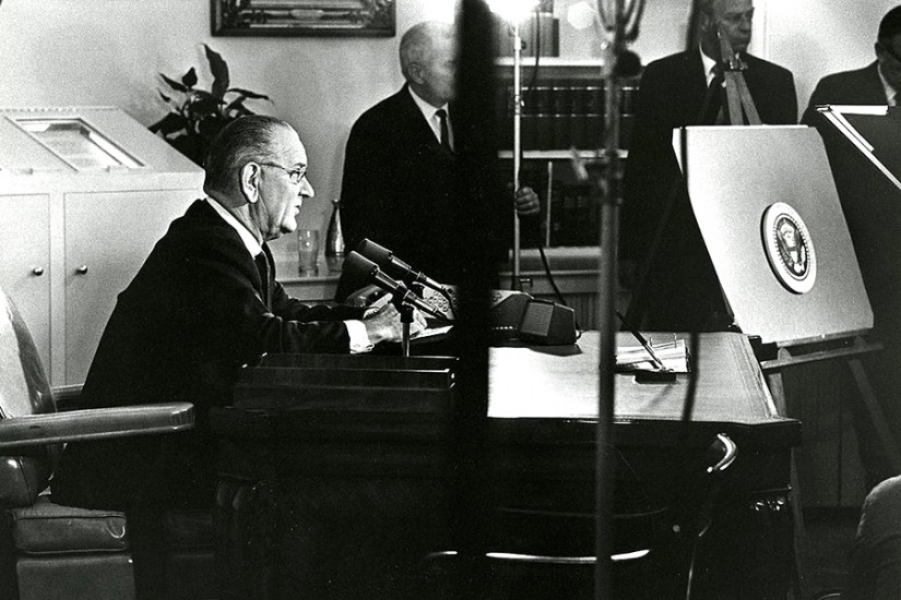President Johnson sits at desk in Oval Office and prepares to address the nation