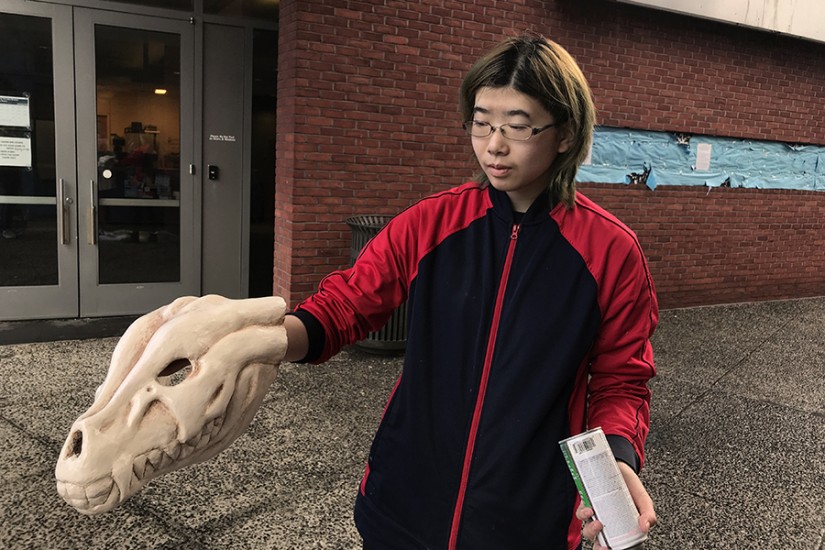 A student holds a mask sculpted to appear like a deer skull