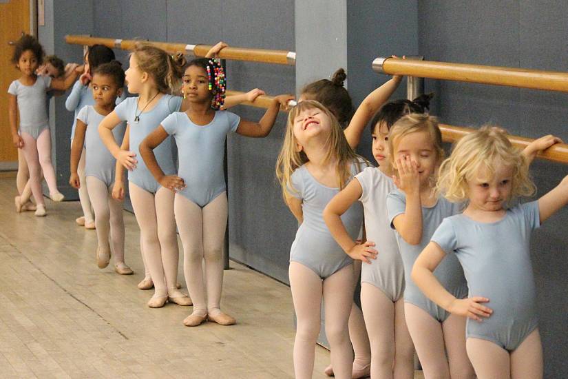 Group of young girls in leotards lined up at a ballet barre