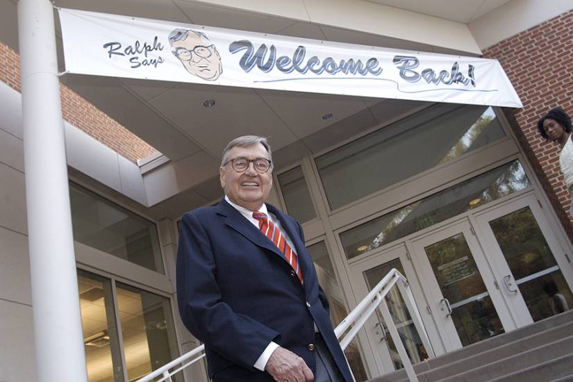 Ralph O'Connor stands on the steps of the rec center, in front of a banner that reads 'Ralph Says Welcome Back!'