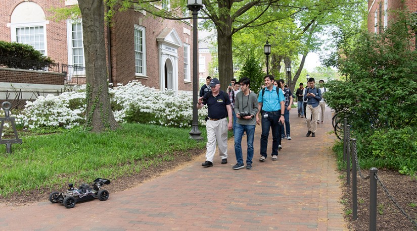 A group walks behind a robot on a brick path