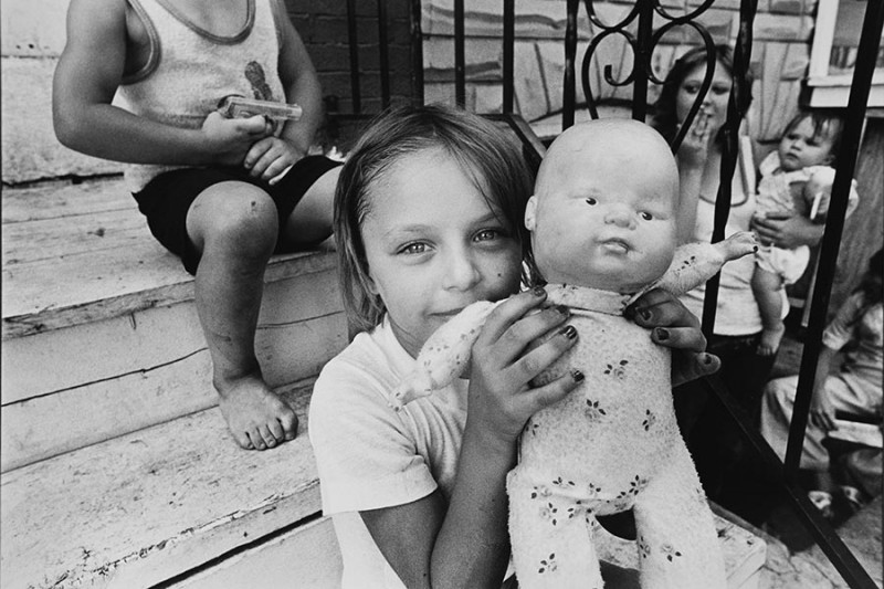 Girl holding doll on stoop