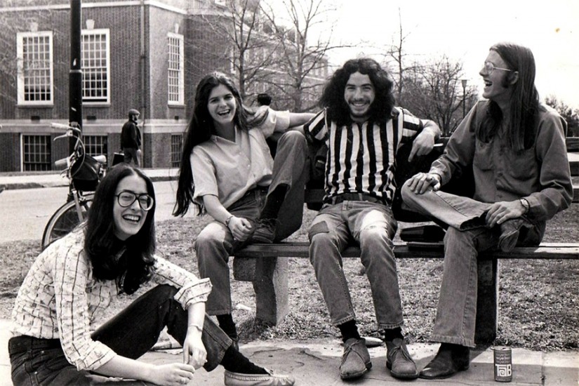 Black and white photo of four students - two male, two female - sitting on a bench