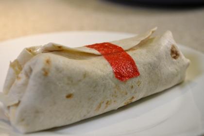 A burrito with red tape keeping it together