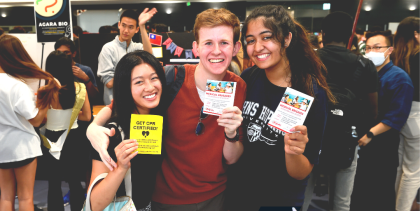 Photograph of a trio of smiling Johns Hopkins students holding club fliers
