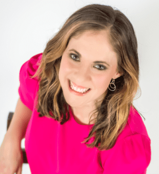 Photograph of Marissa Shuffler, a smiling White woman in a bright pink business dress