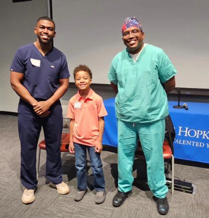 CTY Baltimore Emerging Scholar ZenRa Abdul-Malik, a second grader, meets Dr. Kendall Smith (left) and Dr. Kamal Smith, brothers and CTY alumni, who were guest speakers at the end-of-year celebration. 