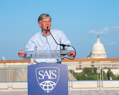 SAIS Dean Jim Steinberg stands at a podium with the U.S. Capitol dome visible behind him