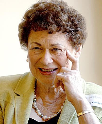 Estelle Fishbein smiles for the camera while leaning her head against her hand.