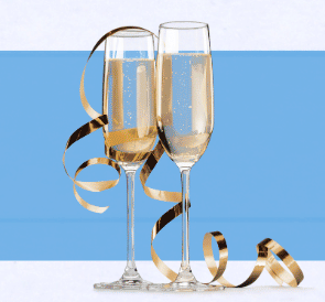 Image of two champagne glasses filled with cider and decorated with a gold ribbon