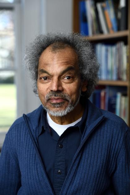 Man smiling at camera with a bookcase in the background