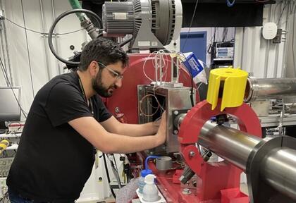 An engineer in a black shirt works on a large red machine.