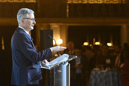 A man speaking from a podium is seen from the side