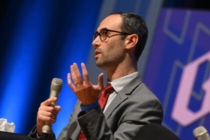 Julian Goresko speaks while holding a microphone.