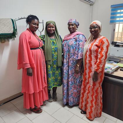 Four women in colorful clothing smile for the camera.