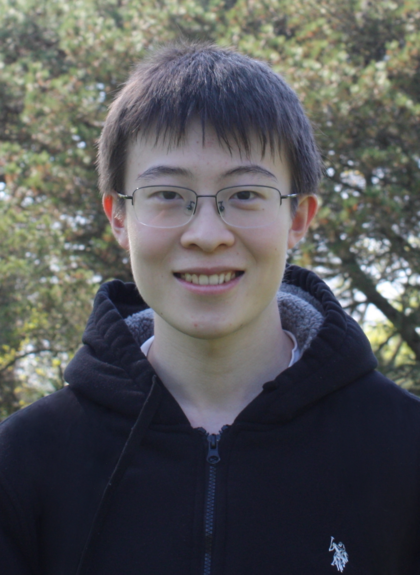 An outdoor photo of Gavin Wang wearing a black hoodie and smiling.