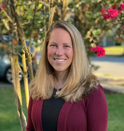 Sarah Ernst smiles for a photo in front of a flowering tree.