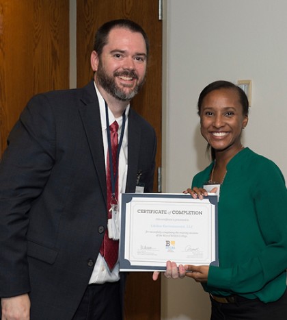 A program director and graduating student pose with the student's diploma