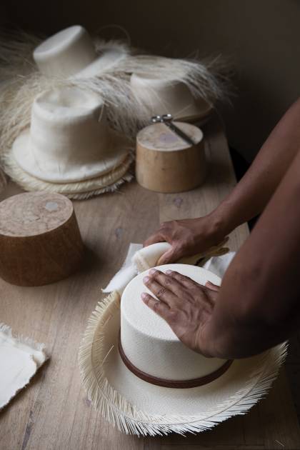 An artisan works with a nearly finished Panama hat
