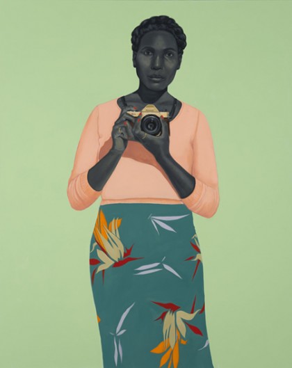 Portrait depicts a black woman holding a camera. Her skin is in a gray tone, and she's wearing a peach colored top and teal skirt with colorful cranes and birds of paradise on it; she stands against a mint green background.