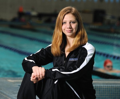 Swimmer Ana Bogdanovski sits next to pool in Johns Hopkins warmup suit