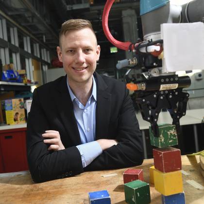 Andrew Hundt sits beside his block-stacking robot