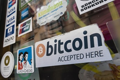 Photo shows a shop window plastered with stickers denoting forms of accepted payment, including a sign for Bitcoin