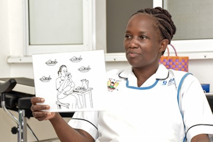 Lorna Othola, a nurse at Ahero Sub-County Hospital, displays a card showing a method of holding a breastfeeding baby