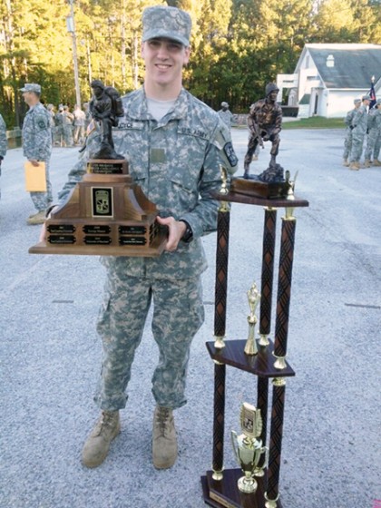 A man in military fatigues holds a trophy