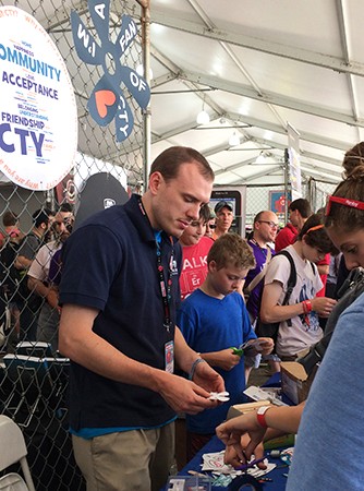 Man in dark blue polo shirt distributes fan parts at crowded expo booth