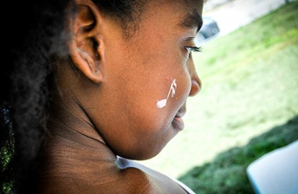 Closeup of a girl with a musical note painted in white on her cheek