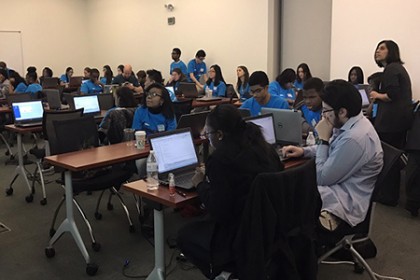 Students sit in a classroom and look at computer screens