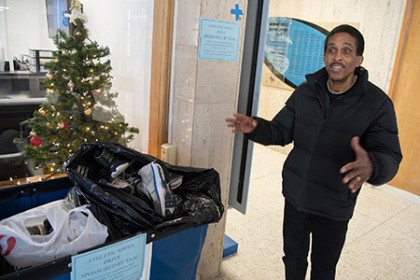 A man stands next to a rolling bin filled with shoes