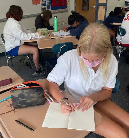 A Roland Park Country School student writes in a notebook while participating in the Changemakers program